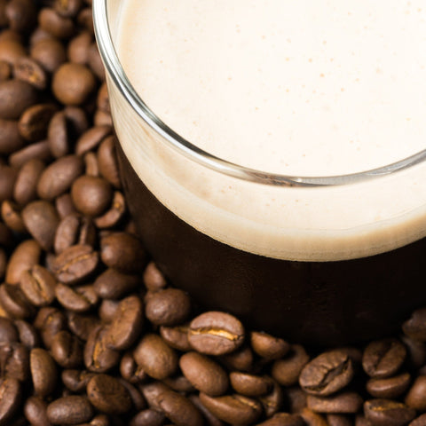 Serving of nitro cold brew coffee surrounded by coffee beans